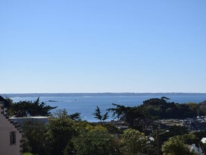 A coastal view with a clear sky, a body of water, and buildings in the foreground.