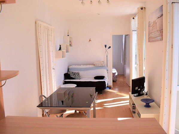 A compact living space with a kitchenette, a dining area, and a bed.