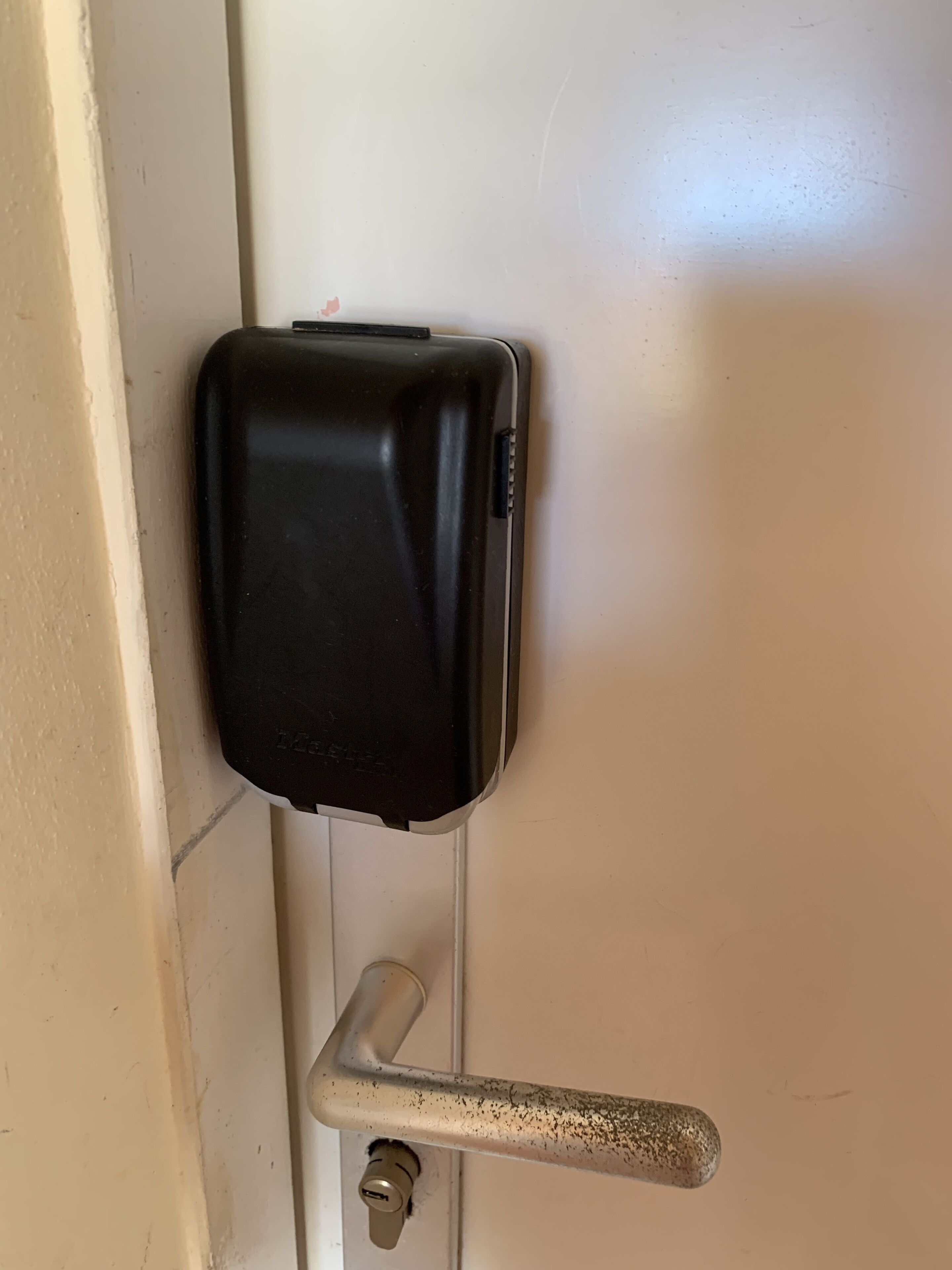 Une porte avec un objet noir fixé dessus, une poignée en métal et un trou de serrure.