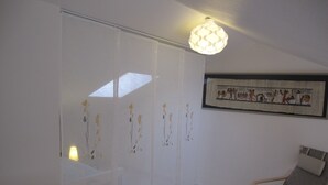 A room with a sliding door, a framed artwork on the wall, a chair, and a lamp on a bedside table. - T2 apartment wonderful sea view, WLAN available garage 2 bicycles available  (Saint-Hilaire-De-Riez)