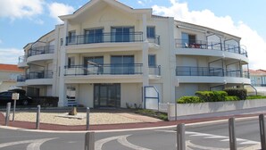 A multi-story hotel with balconies, a central entrance, and a parking area. - T2 apartment wonderful sea view, WLAN available garage 2 bicycles available  (Saint-Hilaire-De-Riez)