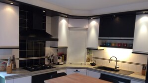 A modern kitchen with black and white cabinetry, a wooden dining table, and a black kettle on the countertop. - House with pool in the heart of the Castles of the Loire (Cour-Cheverny)