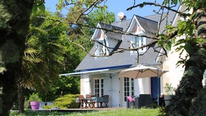 A house with a covered patio, outdoor furniture, and a lawn with white flowers. - House with pool in the heart of the Castles of the Loire (Cour-Cheverny)