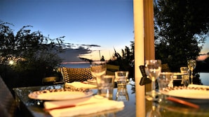 A dining table set for two with a view of the evening sky and mountains. - Magnificent and luxurious 4-star T2 with sea view, swimming pool and garden (Saint-Gilles-Les-Bains)