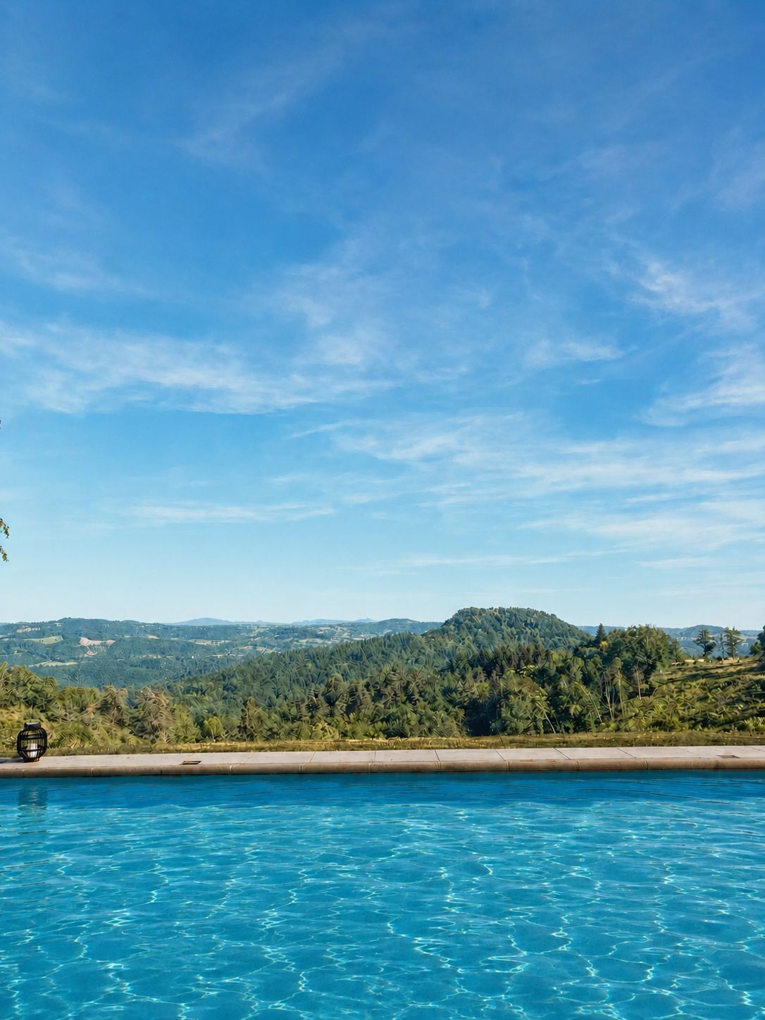 A clear blue sky above a swimming pool with a view of a hilly landscape in the distance.