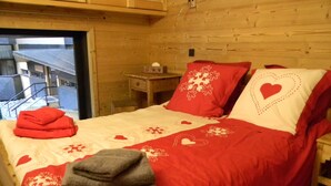 A wooden cabin bedroom with a bed, pillows, and a blanket.