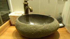 A stone basin sink with a faucet on a wooden countertop.