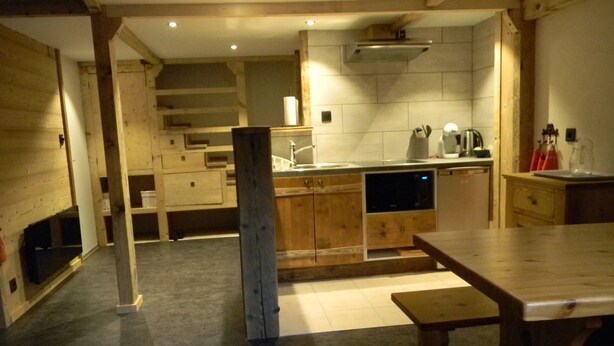 A kitchen with wooden cabinets, a sink, a microwave, and a dining area with a table.