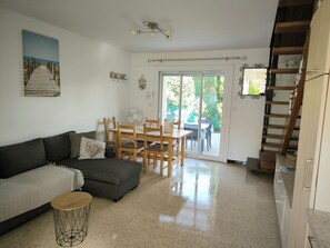 Ein Wohnzimmer mit einer Couch, einem Esstisch mit Stühlen, einem Ventilator und einer Treppe.