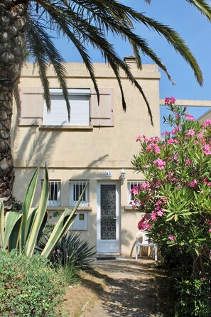Ein zweistöckiges Gebäude mit einer beigen Fassade, einer weißen Tür und einem Balkon mit weißer Brüstung.