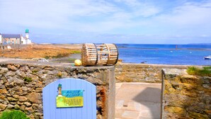 Vista costiera con un faro, un muro di pietra e una botte di legno.