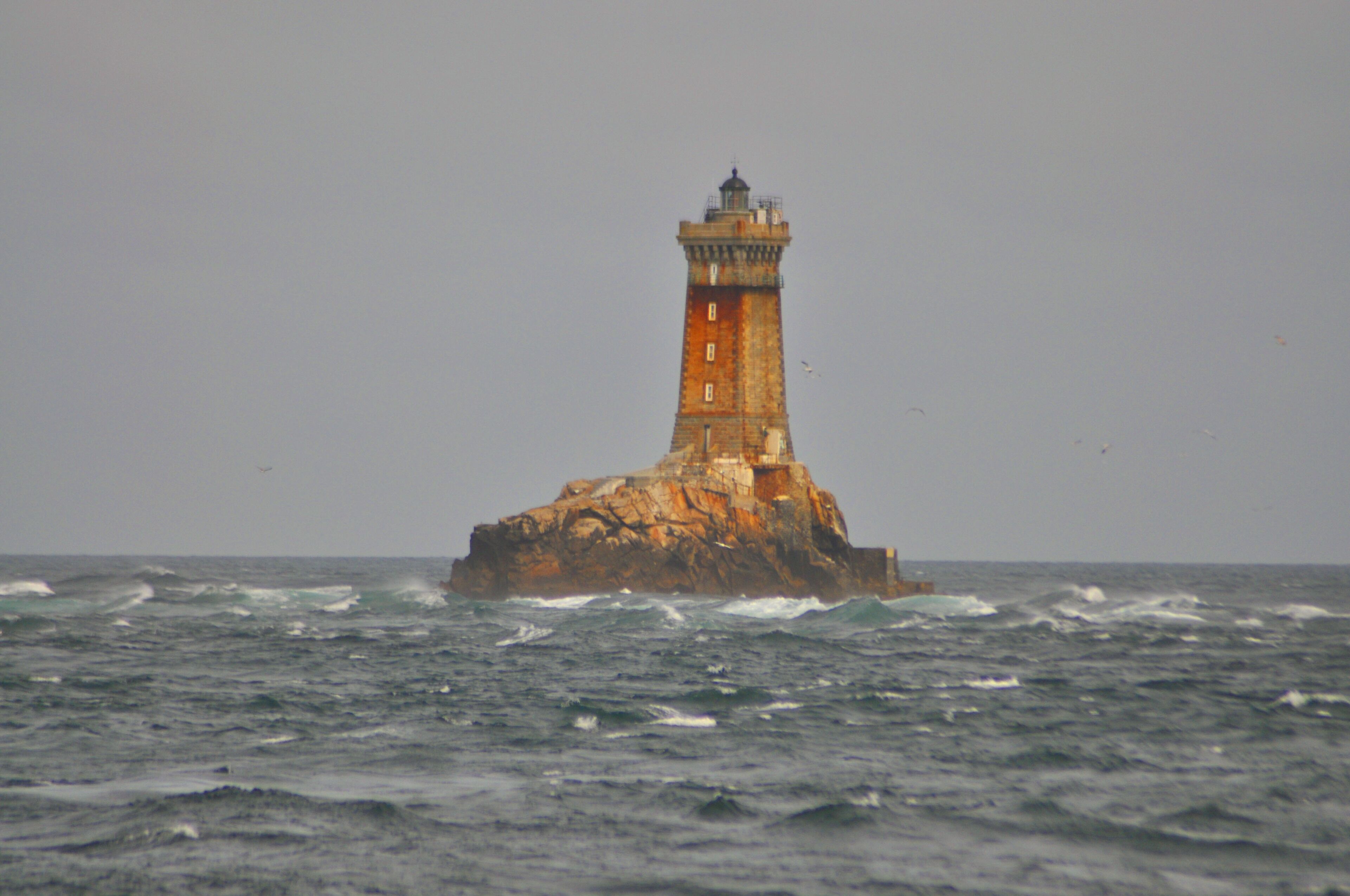 Ein Leuchtturm auf einem Felsen im Meer.