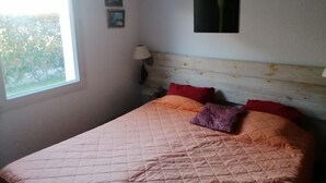 Ein Schlafzimmer mit Bett, Fenster und Wandbild.