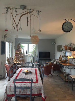 Un coin repas avec un sapin de Noël, une horloge et un téléviseur en arrière-plan.