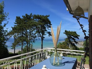A terrace with a clear view of the sea, a vase with pampas grass, and a table with a blue tablecloth. - L'ENVIE DU LARGE: charming rental sea view, pink granite coast (Louannec)