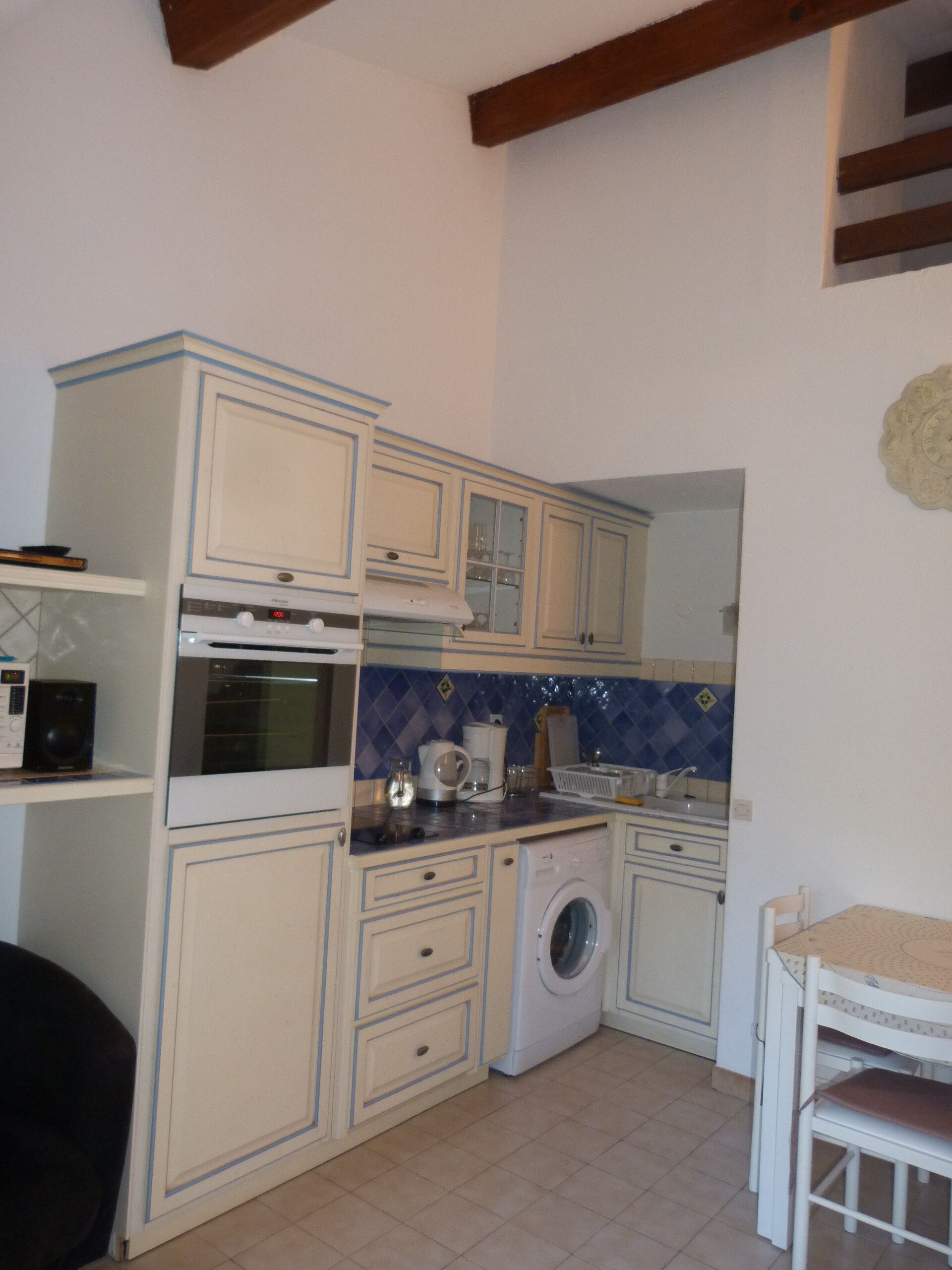 A compact kitchen with a washing machine, a microwave, and a stove.