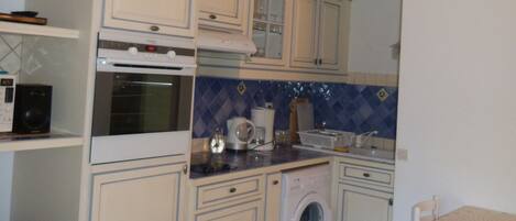 A compact kitchen with a washing machine, a microwave, and a stove.