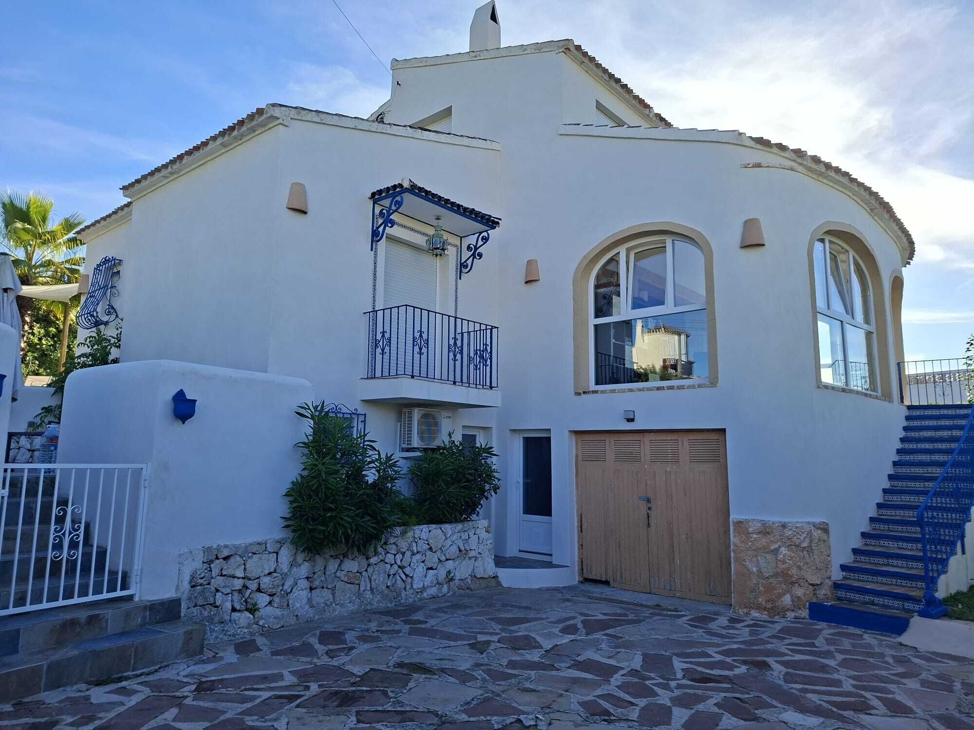 A two-story building with a stone-paved courtyard, a wooden garage door, and a blue staircase.