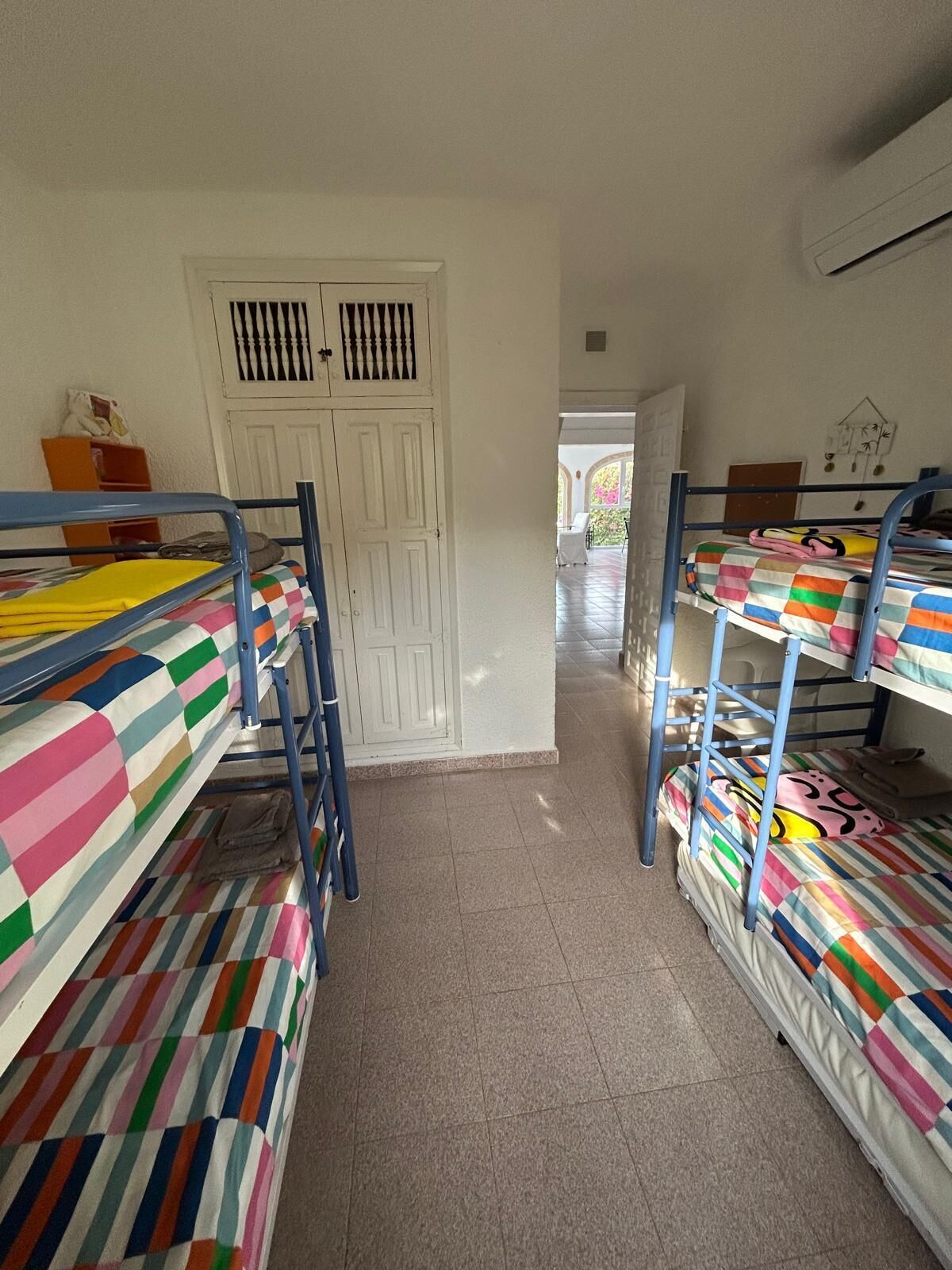 A dormitory room with bunk beds, a white door, and a tiled floor.