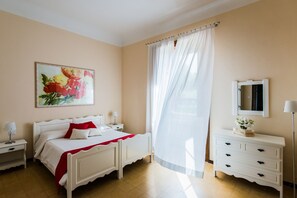 A bedroom with two single beds, a bedside table with a lamp, a dresser with drawers, a mirror, and a large window with sheer curtains. - Villa with swimming pool, jacuzzi and tennis, in front of the Aeolian Islands  (Messina)