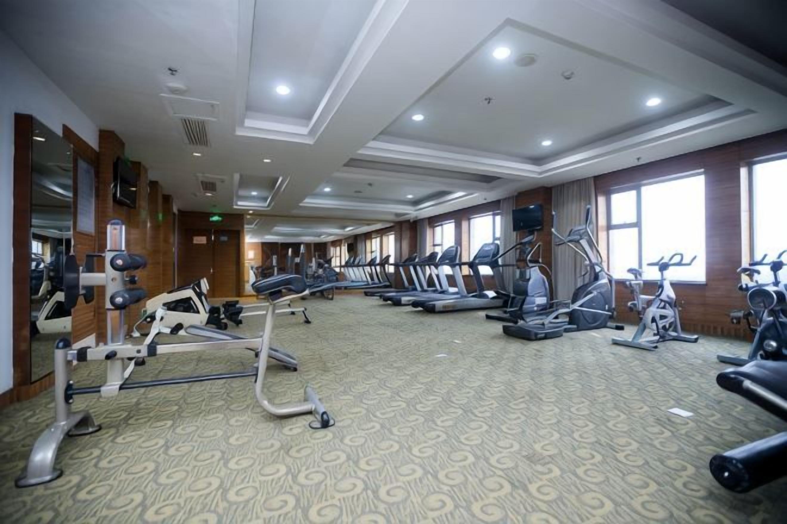 Un gimnasio con cintas de correr, elípticas y equipo de pesas.
