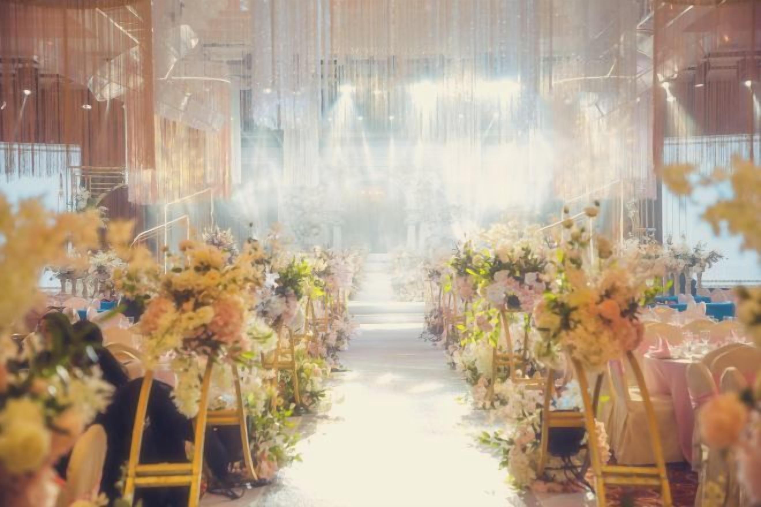 An aisle with floral arrangements and chairs, suggesting a formal event setting.
