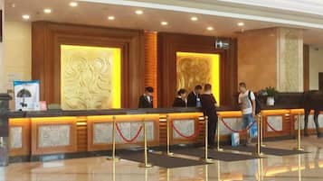 Zona de recepción de un hotel, con mostrador, área de espera y un muro decorativo.