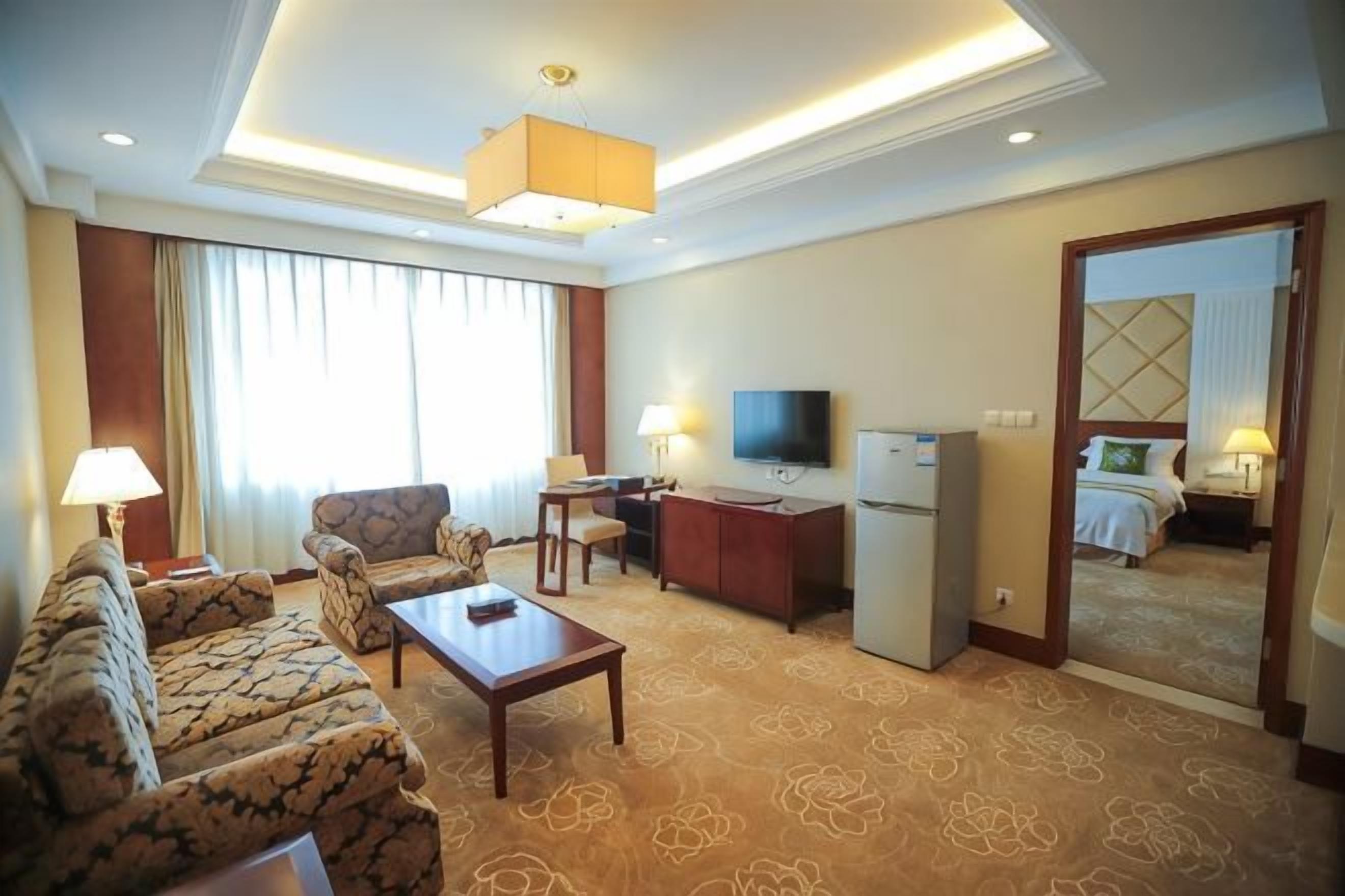 Habitación de hotel con un sofá, una mesa de centro, un televisor, un escritorio y una cama.