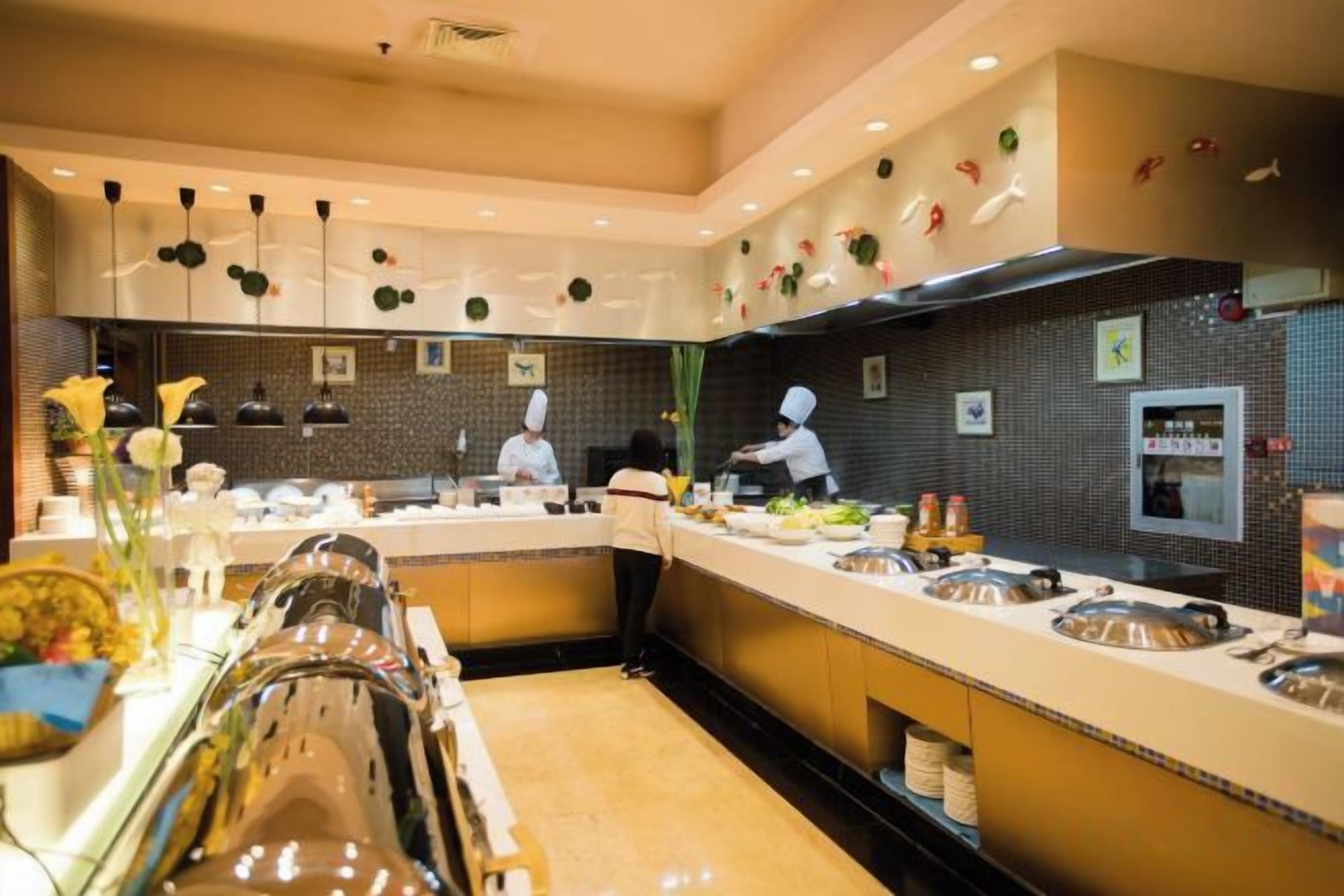 A modern kitchen with a long counter, multiple food stations, and a chef preparing food.
