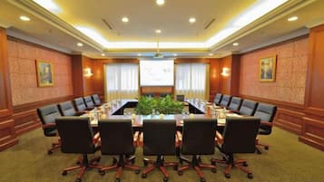 Un salón de conferencias con una larga mesa, varias sillas y una pantalla para proyector.