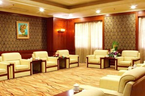 A hotel room with a large seating area, a wooden accent wall, and a painting. - Perfect International Hotel (Qidong)