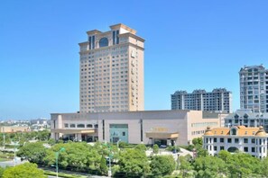 A hotel with a prominent tower, multiple floors, and a central entrance. - Perfect International Hotel (Qidong)