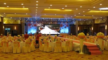 Un salón de banquetes con mesas redondas, un escenario y una pantalla grande.