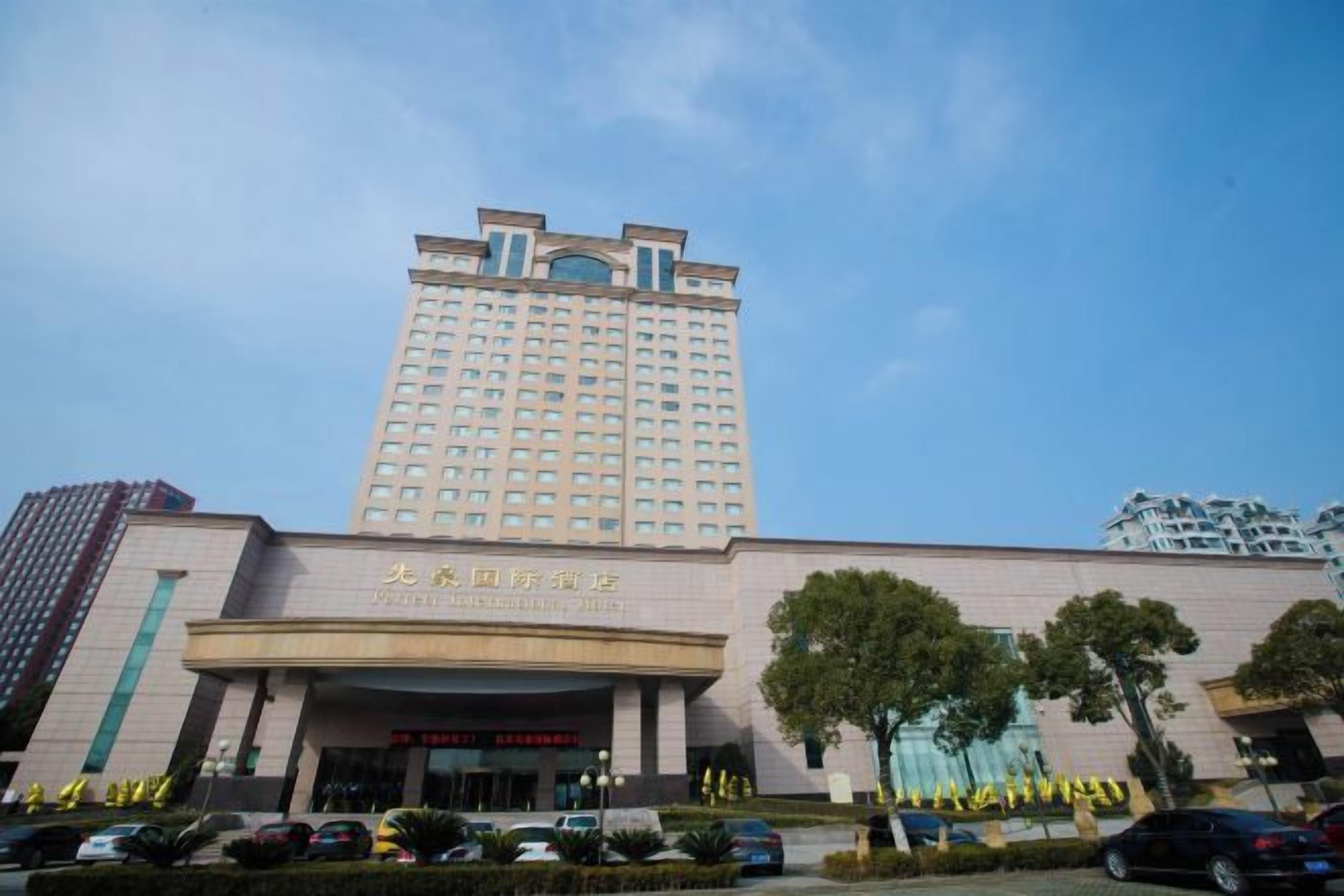 Un hotel de varios pisos con una entrada destacada y un edificio grande al fondo.
