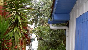 Un callejón estrecho con plantas en macetas y un edificio con contraventanas azules.