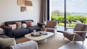 Una sala de estar moderna con un sofá, sillones, una mesa de centro y un ventanal con vistas a la vegetación y un paisaje lejano.