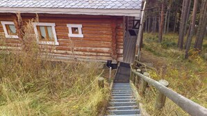 A wooden cabin with a metal staircase leading to a wooden deck.
