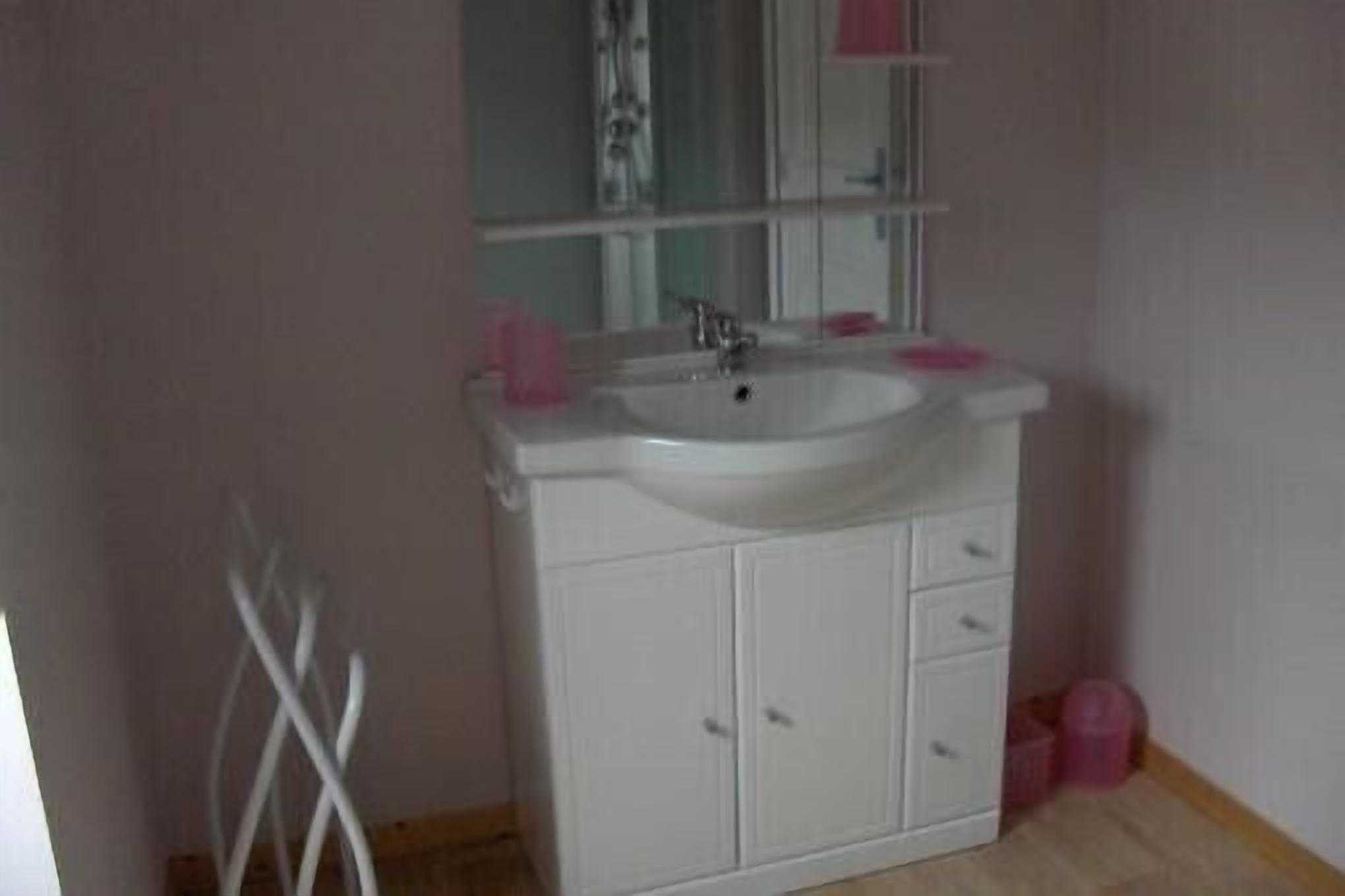 A bathroom with a white sink, mirror, and cabinets.