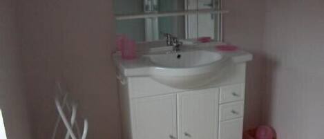 A bathroom with a white sink, mirror, and cabinets.
