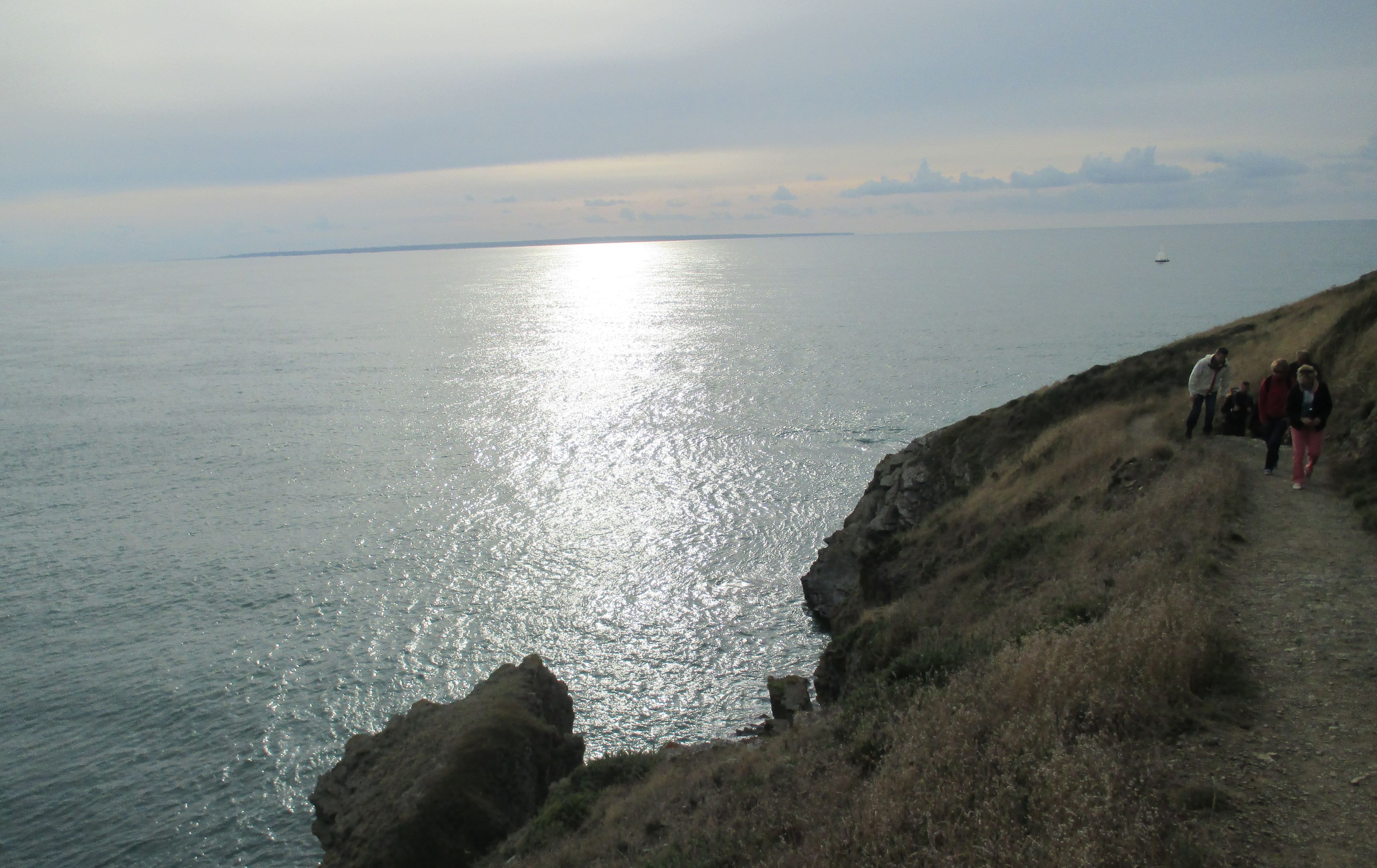 A coastal path with rocky terrain and a view of the sea.