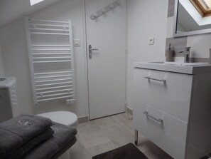 Ein Badezimmer mit Toilette, Handtuchhalter, Waschbecken und Spiegel.