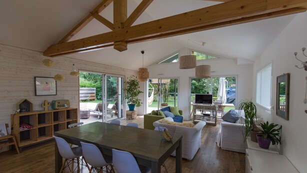 A spacious living area with a wooden ceiling, a dining table with chairs, a sofa, and a TV. - Villa 6 pers / with heated pool / near golf & beach / Holiday home (Moliets-Et-Maa)