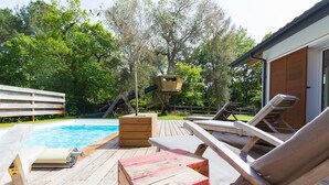 A wooden deck with lounge chairs, a pool, and a wooden play structure. - Villa 6 pers / with heated pool / near golf & beach / Holiday home (Moliets-Et-Maa)