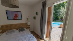 A bedroom with a large bed, a view of a swimming pool, and a sliding glass door leading to an outdoor area. - Villa 6 pers / with heated pool / near golf & beach / Holiday home (Moliets-Et-Maa)
