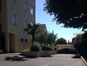 A residential building with a gated entrance, a palm tree, and a clear blue sky.
