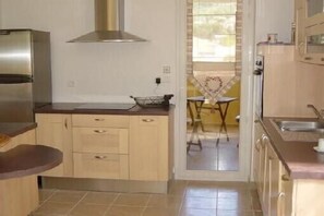 A compact kitchen with a stainless steel refrigerator, a gas stove, and a sink.