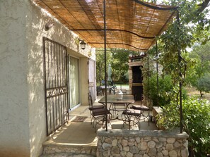 Um pátio externo com paredes de pedra, uma mesa com cadeiras e uma lareira de pedra.