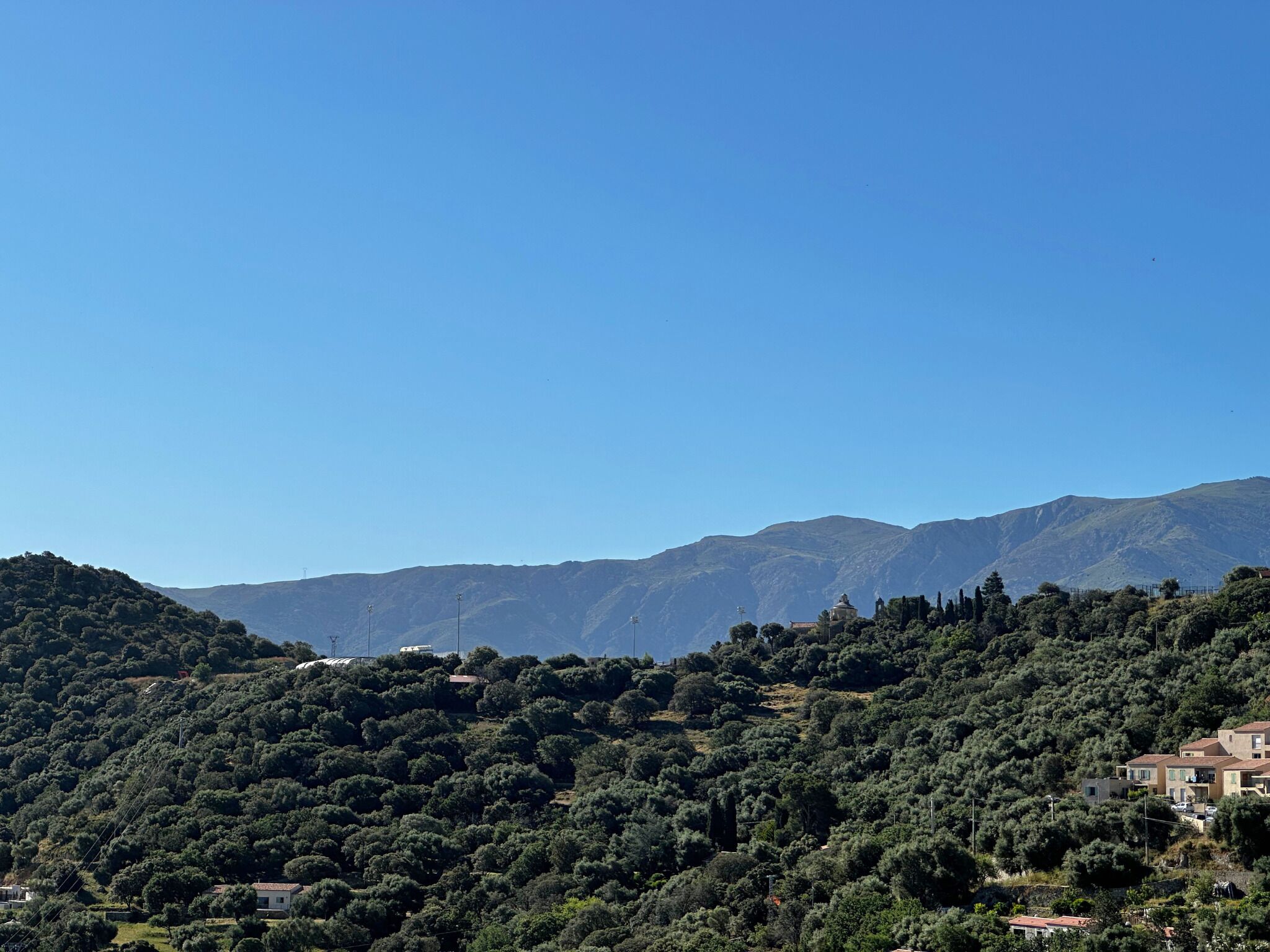 A mountainous landscape with dense greenery and scattered buildings.