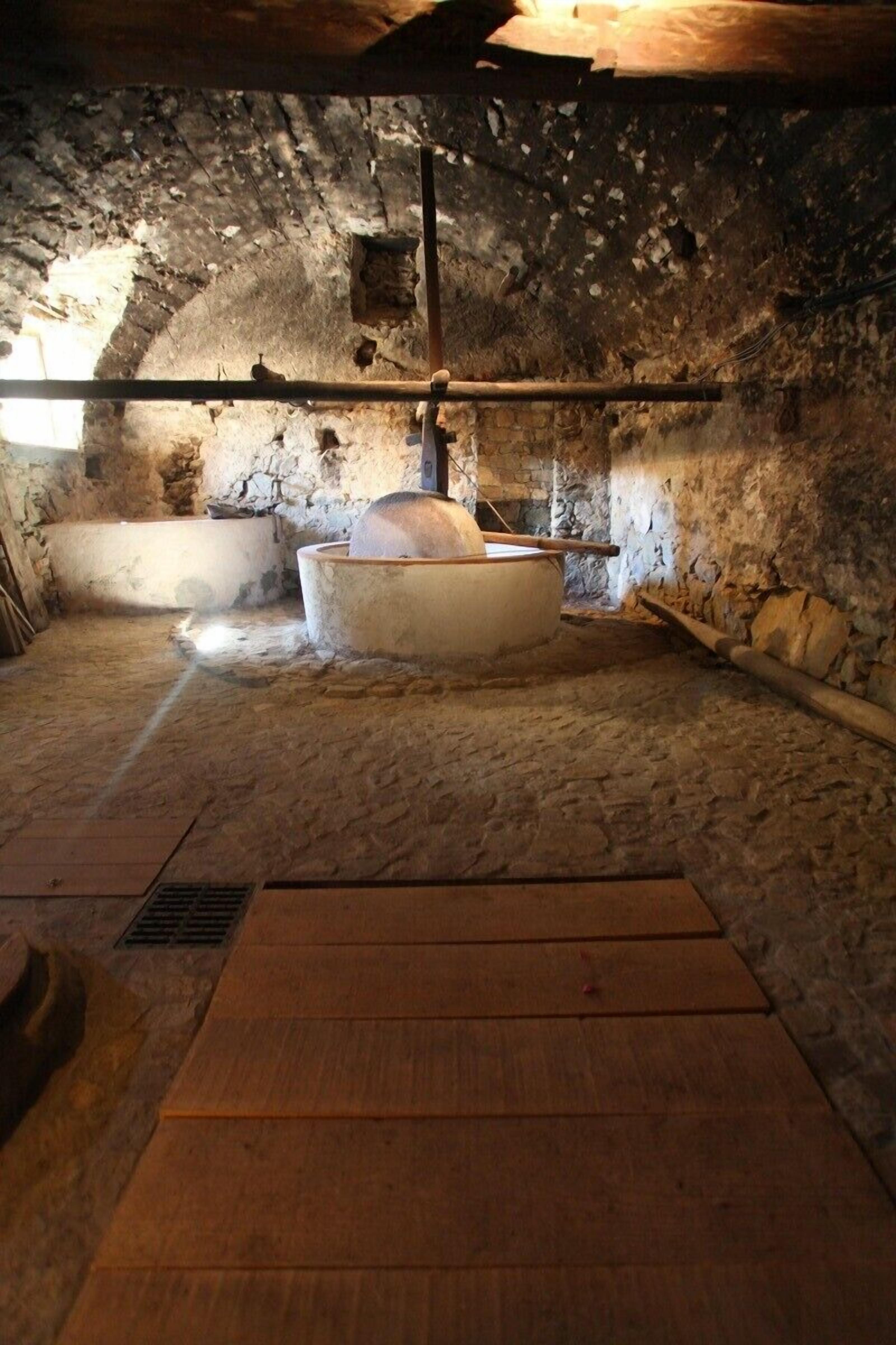 Une pièce aux murs de pierre, dotée d’une grande baignoire et d’un banc en bois.