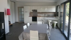 A modern kitchen with white cabinets, a built-in oven, and a dining area with a table and chairs. - Detached family home in the bay of mont saint michel in Cherrueix (Cherrueix)